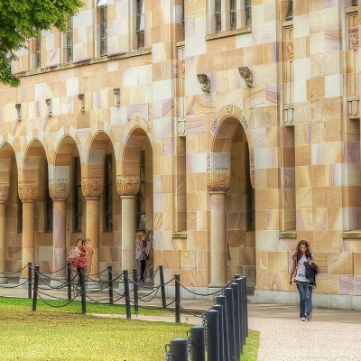 UQ's campus - A large sandstone building with archways and a green lawn in front.